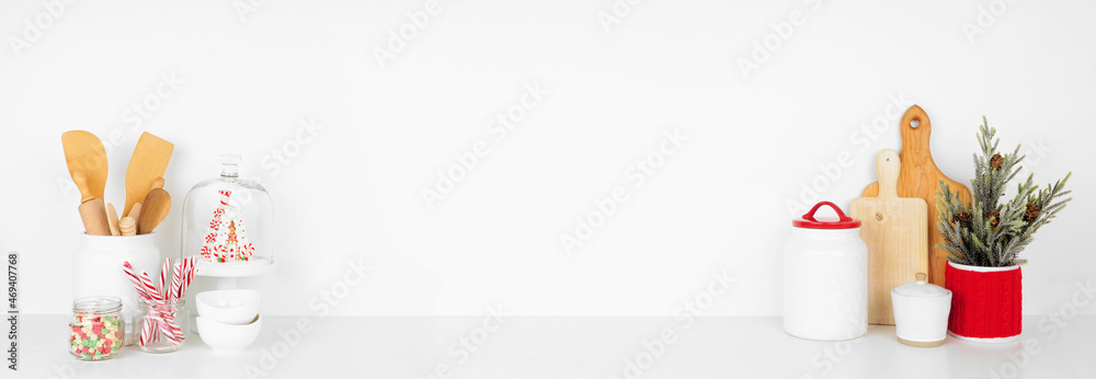 Christmas theme kitchenware, decor and sweets on a white shelf or counter forming a frame. Banner against a white wall background with copy space. - obrazy, fototapety, plakaty 