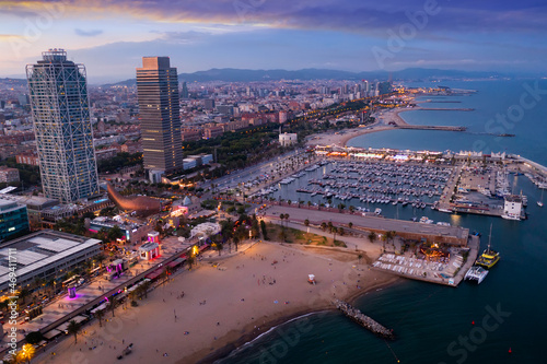 Picturesque evening aerial view of coastal area of Barcelona overlooking Olympic Harbor marina with moored pleasure yachts and modern architecture of waterfront in summer, Spain..