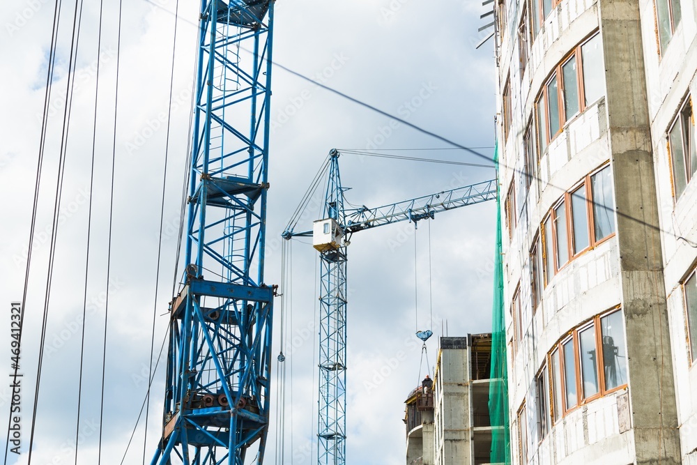 Large construction site including several cranes working on a building complex, with clear blue sky and the sun Large construction site including several cranes working on a building complex, with clear blue sky and the sun