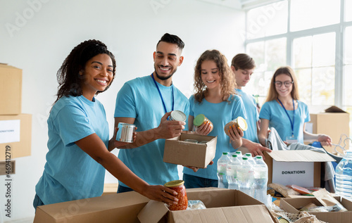 Slika na platnu Diverse group of volunteers sorting donated food in boxes, working in community