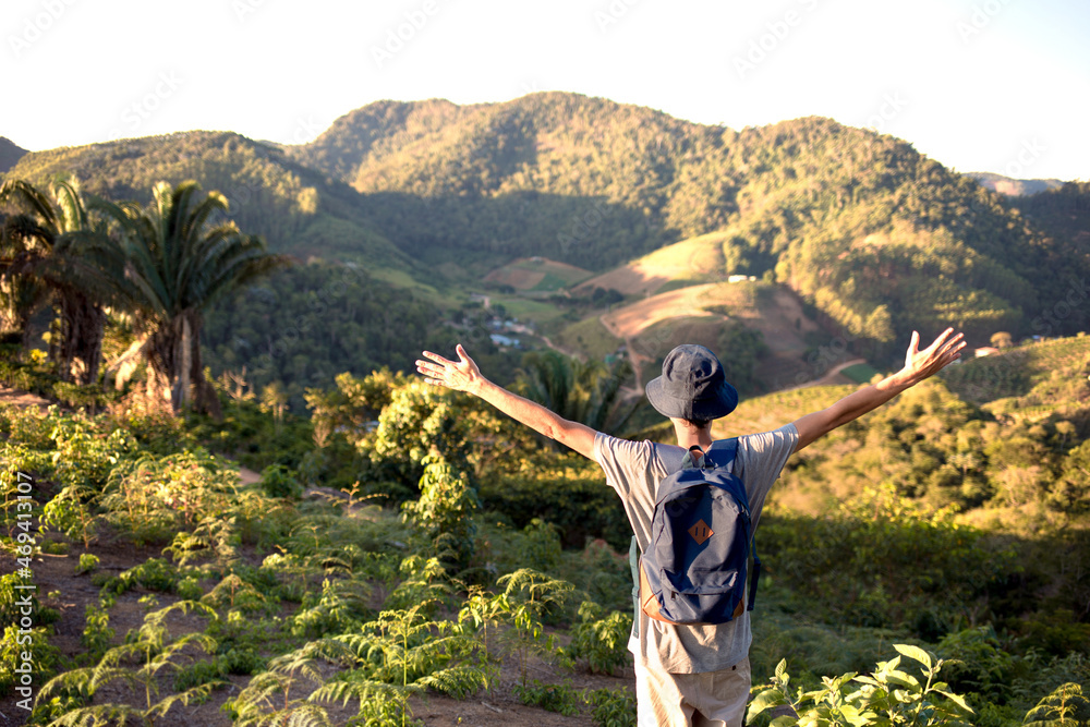 Young man with his arms raised contemplating the mountains landscape in front of him. Freedom, adventure and travel concept.