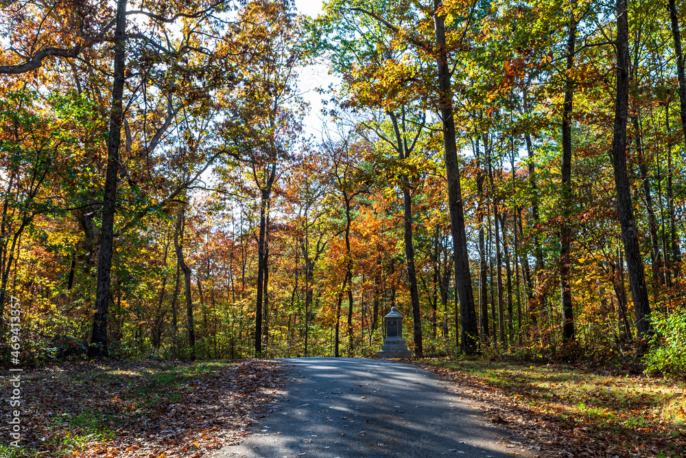 Obraz premium A road through the woods in the Gettysburg National Military Park on a sunny fall day