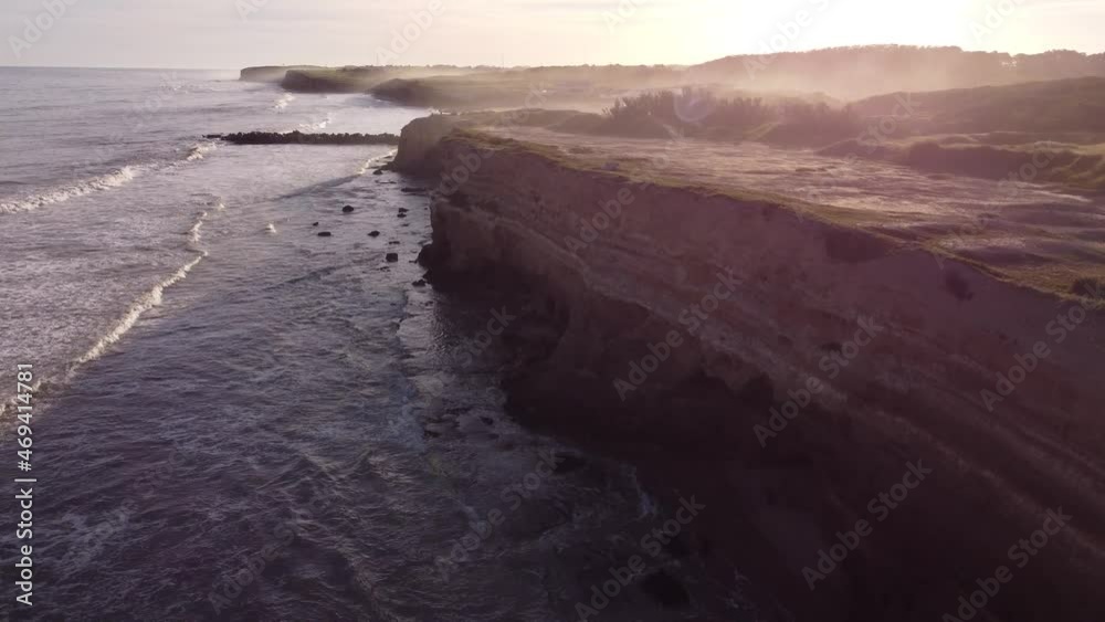 Cinematic Aerial shot along big cliffs during sunset on Atlantic Ocean - Beautiful lighting in background - Mar del Plata,Argentina Cinematic Aerial shot along big cliffs during sunset on Atlantic Ocean - Beautiful lighting in background - Mar del Plata,Argentina