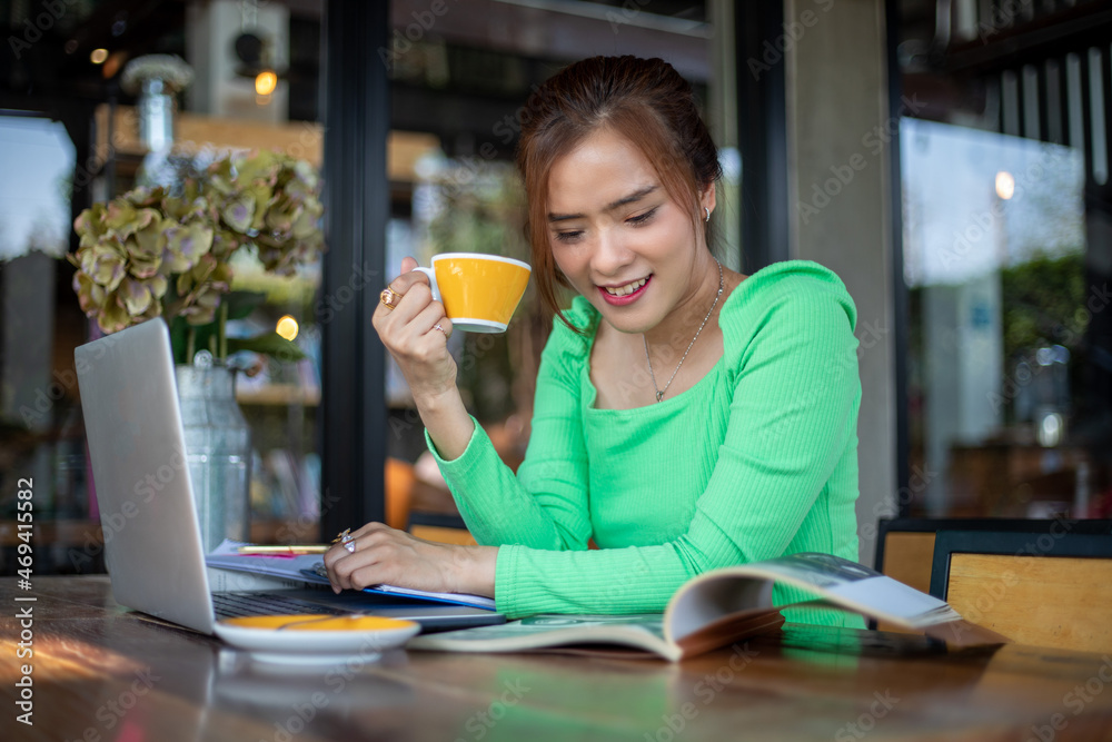 Asian women reading book and smiling and happy Relaxing in a coffee shop after working in a successful Asian women reading book and smiling and happy Relaxing in a coffee shop after working in a successful
