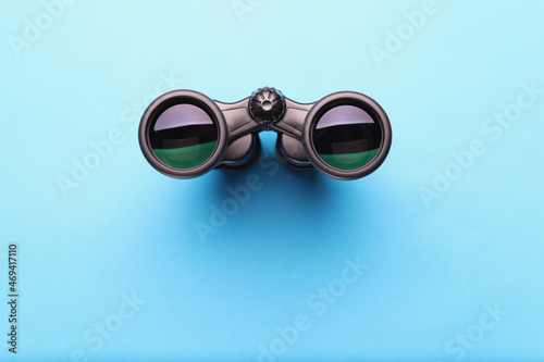 Binoculars equipment placed on blue background with shadow