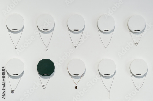 Two rows of silver chains on round hangers with pricetags as part of large display in jewellery store photo