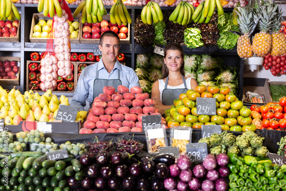 Glad male and female shop assistants in vegetable shop