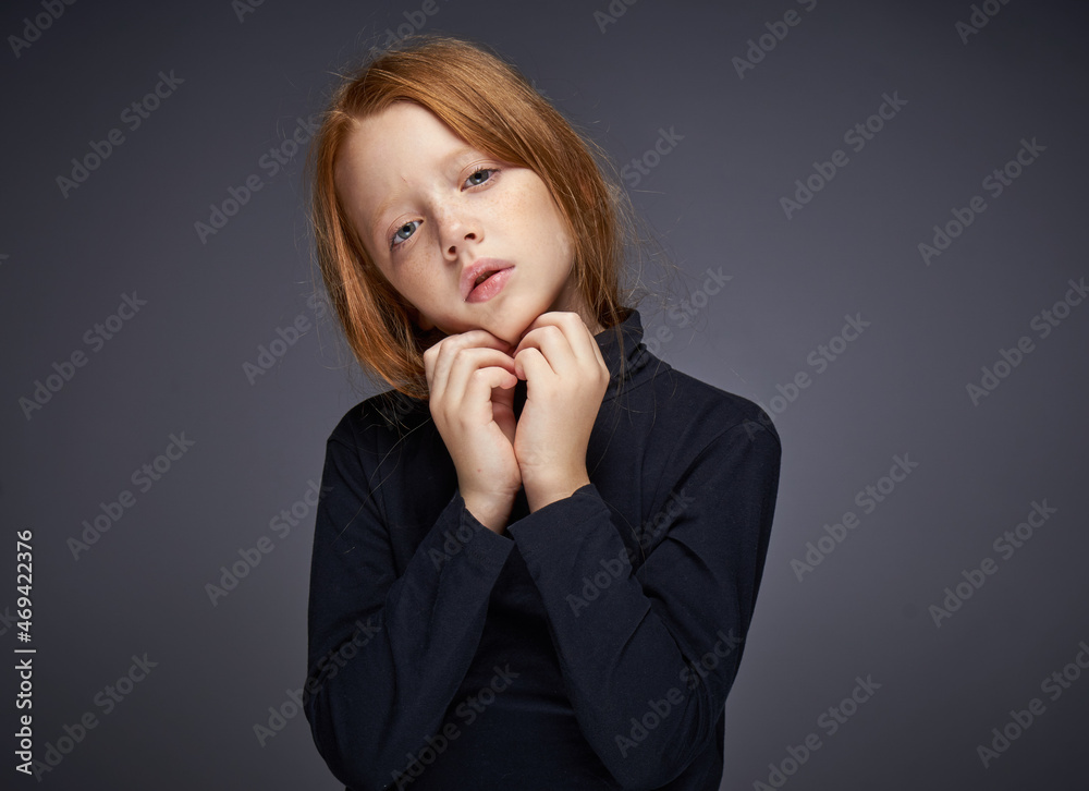 red-haired girl with freckles on her face in a black sweater posing red-haired girl with freckles on her face in a black sweater posing