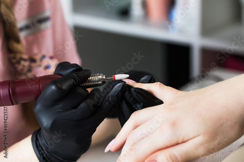  A manicurist removes gel polish from nails using a milling cutter. Hardware manicure close-up. Coating shellac on nails