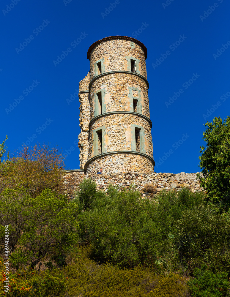 View of tall round main tower of ancient ruined castle in French village of Grimaud on sunny autumn day, Var department