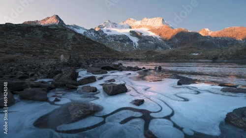 Frozen lake with sunrise over Bernina ridge, Time lapse of switerland mountains photo