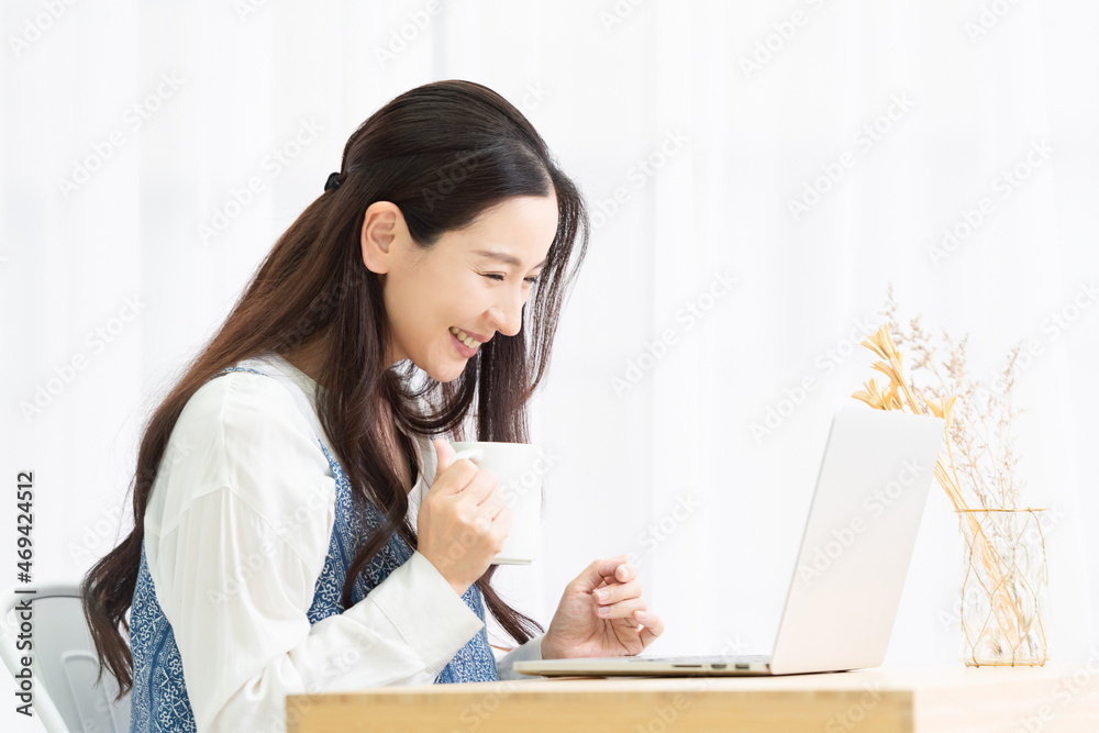 リビングでノートパソコンを使う主婦 リビングでノートパソコンを使う主婦