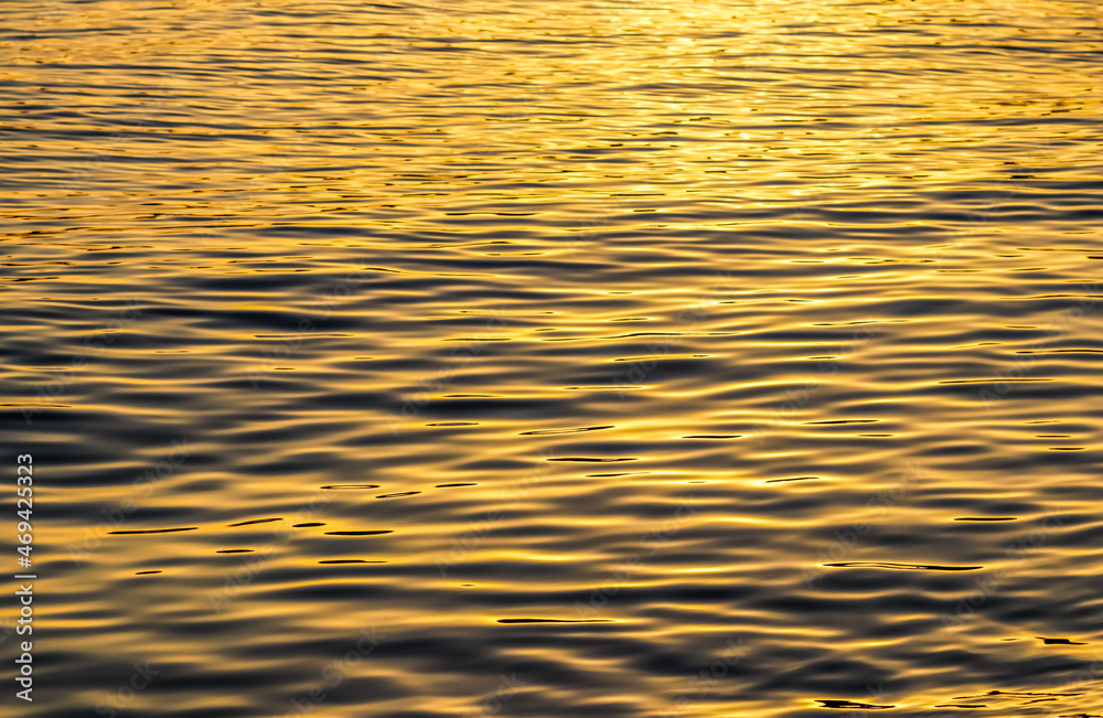 Golden sea waves in sunset glow as surface background. Summer holidays and coastal nature concept