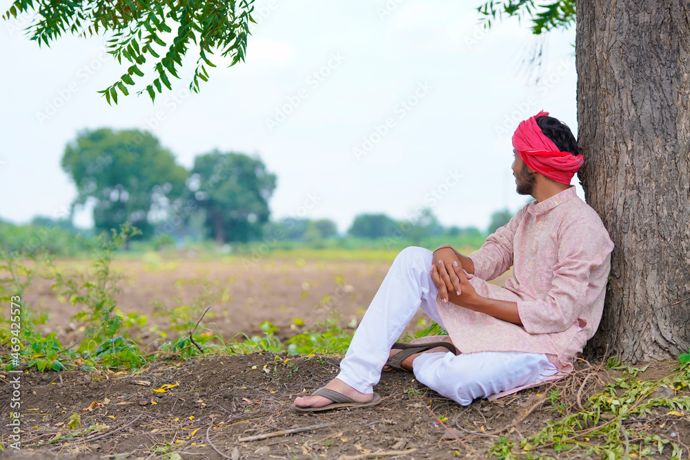 Young indian farmer sitting at agriculture field. - obrazy, fototapety, plakaty 