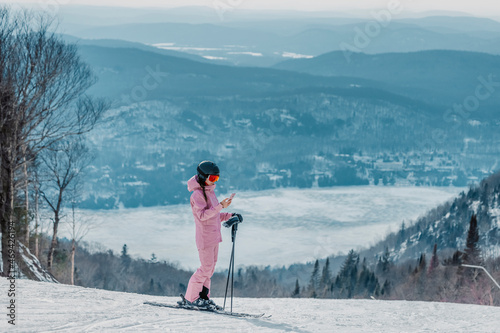 Canvastavla Phone on ski vacation - Woman skier using phone app on ski trail slope in amazing winter nature landscape