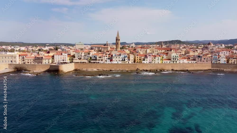 Drone clip over the blue ocean with the scenic town of Alghero in Sardinia, Italy extending along the background Drone clip over the blue ocean with the scenic town of Alghero in Sardinia, Italy extending along the background