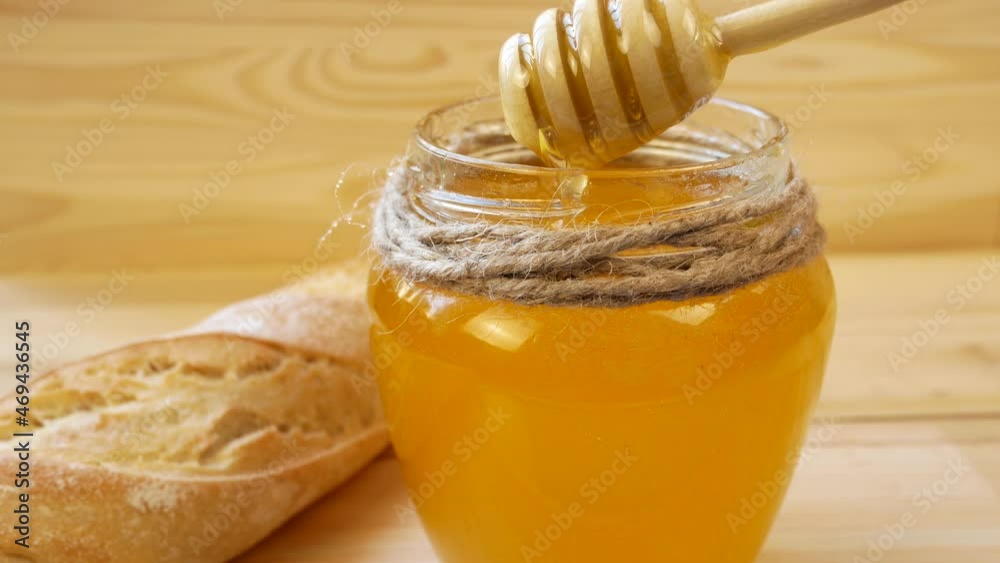 Golden liquid honey flows from a spoon into a jar. Organic food, healthy food concept Golden liquid honey flows from a spoon into a jar. Organic food, healthy food concept
