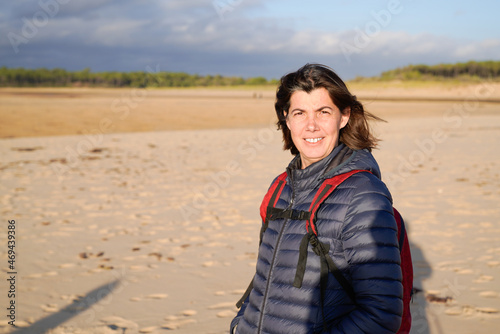 Beautiful happy woman happy smile in winter walking on ocean sand coast beach