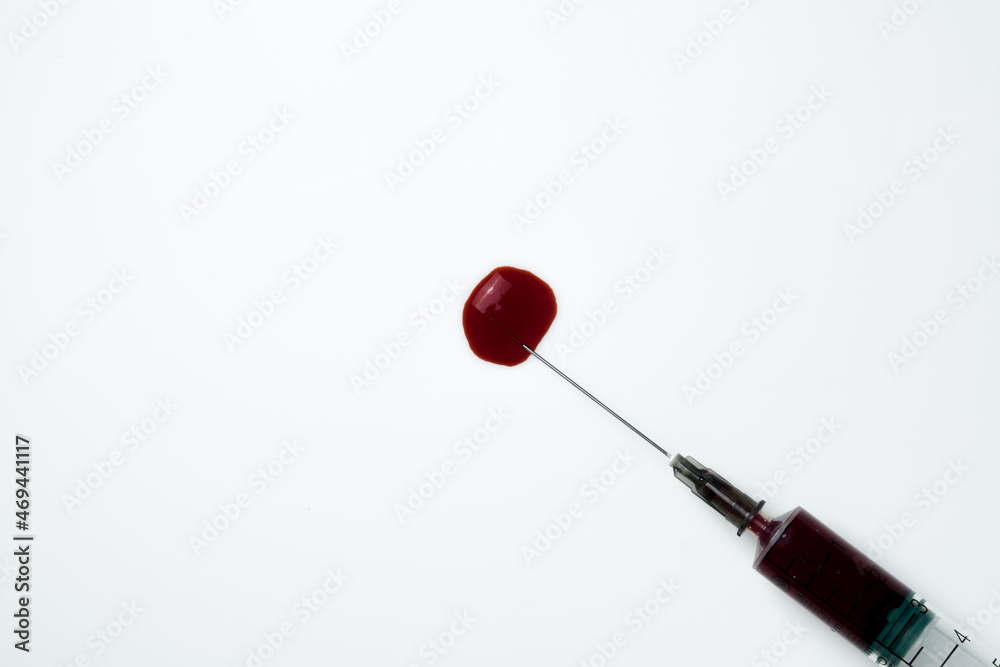Medical syringe and needle with a drop of blood on a light background Medical syringe and needle with a drop of blood on a light background