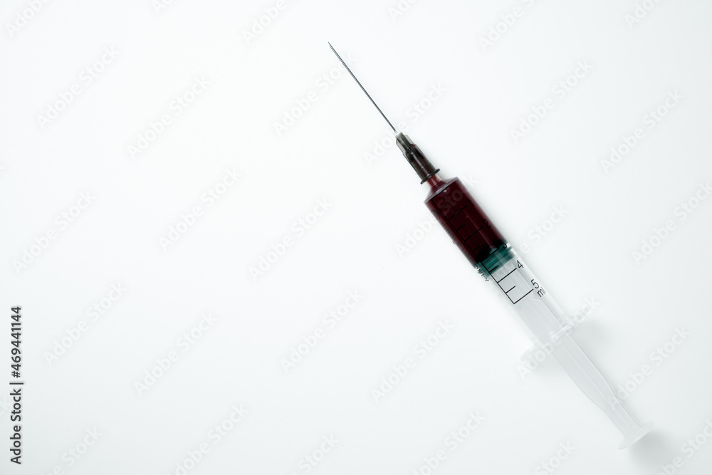Medical syringe and needle with red blood on a light background Medical syringe and needle with red blood on a light background