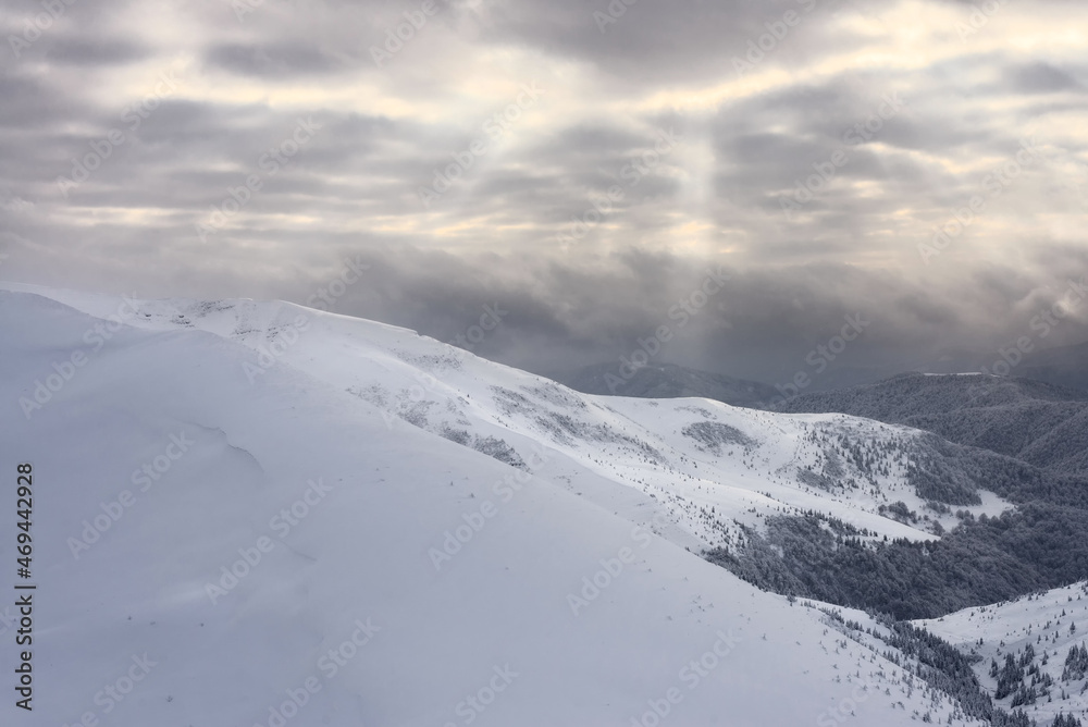 Snow-covered mountain slopes against the backdrop of a cloudy sky. Snow-covered mountain slopes at sunset. Snow-covered mountain slopes against the backdrop of a cloudy sky. Snow-covered mountain slopes at sunset.