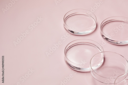 Petri dishes with water and ripple in light pink background for skincare