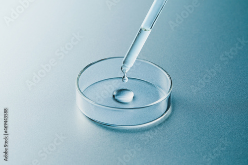 Petri dish and dropper with liquid in silver blue background photo