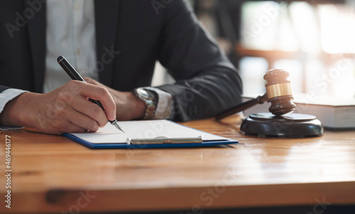 businessman hand writing note on clipboard. Real estate concept, judge gavel or lawyer in auction with house model.