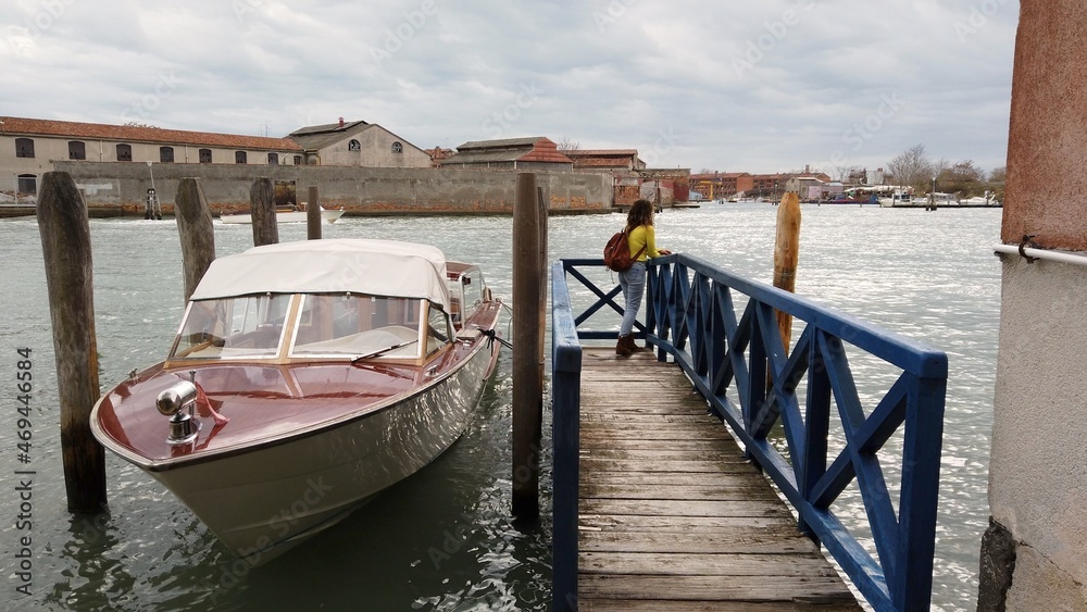 Europe, Italy , Venice - girl admires the beauty of murano and Venice, the city of love, walking along the river - goes up on the wooden bridge to see the lagoon with boats and gondolas