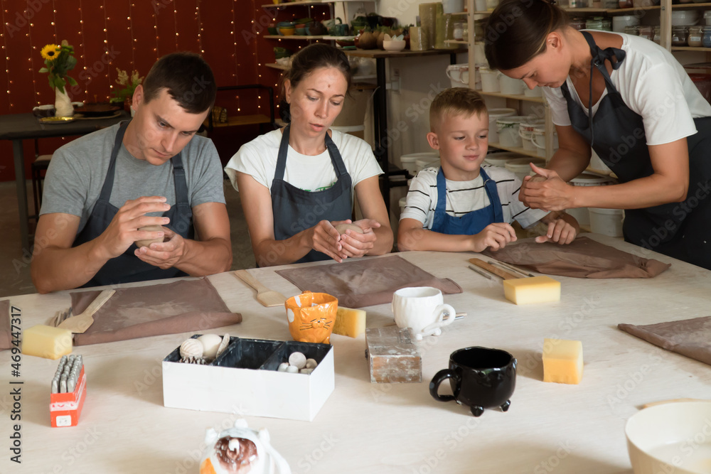 Family spending time together in pottery school. Woman,man and boy sculpting mugs Family spending time together in pottery school. Woman,man and boy sculpting mugs