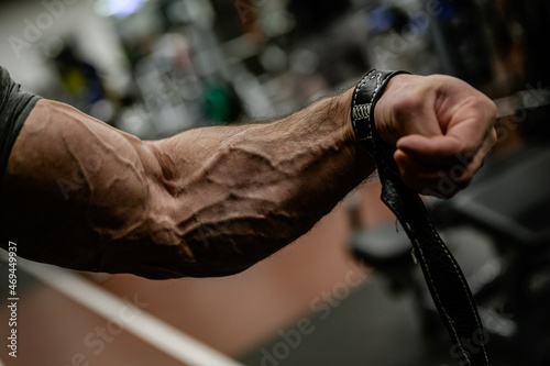 strong forearm with vein and strap of bodybuilder athlete male during sport fitness gym training