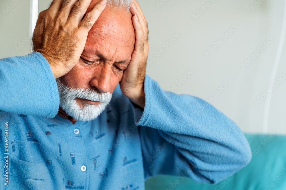 Depressed senior man patient suffering from headache and illness in hospital. Healthcare concept Depressed senior man patient suffering from headache and illness in hospital. Healthcare concept