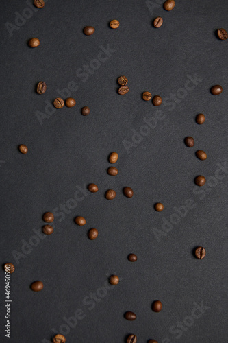 Flat lay composition of scattered fresh roasted coffee beans on a black background with copy space for advertisement
