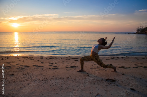 Crescent Lunge with Cactus Arms. Asian woman doing yoga poses on a beach in Koh Pha Ngan island, Thailand