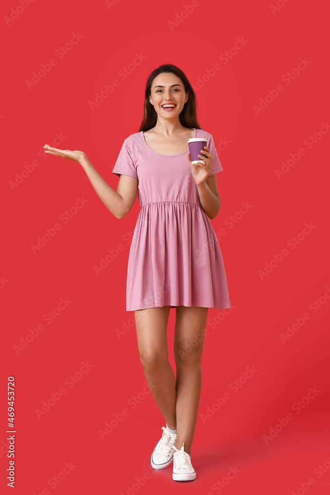 Beautiful woman with cup of coffee showing something on color background Beautiful woman with cup of coffee showing something on color background