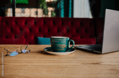composition a cup of coffee, glasses and a laptop on the table