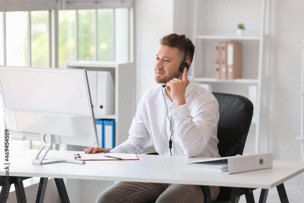 Handsome consultant of call center working at table in office Handsome consultant of call center working at table in office