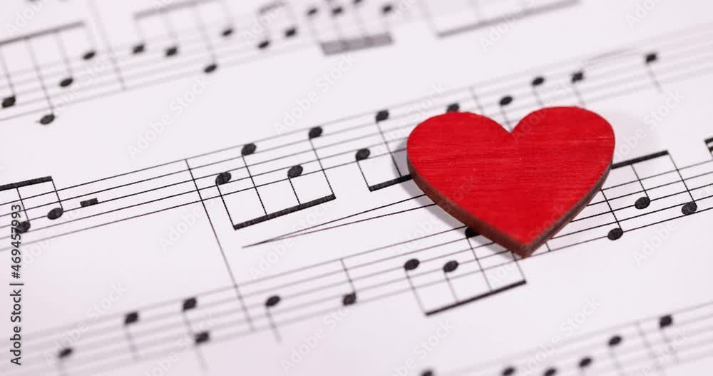 Red wooden heart lies on musical notes slow motion 4k movie