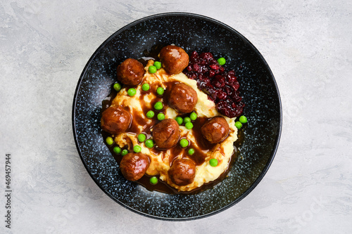 Top view of meatballs with gravy served with mashed potato, green pea and cranberry jam