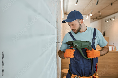 Bearded man drilling wall with hammer drill
