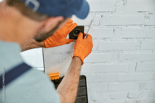 Foto Man hands in work gloves repairing electrical wall socket