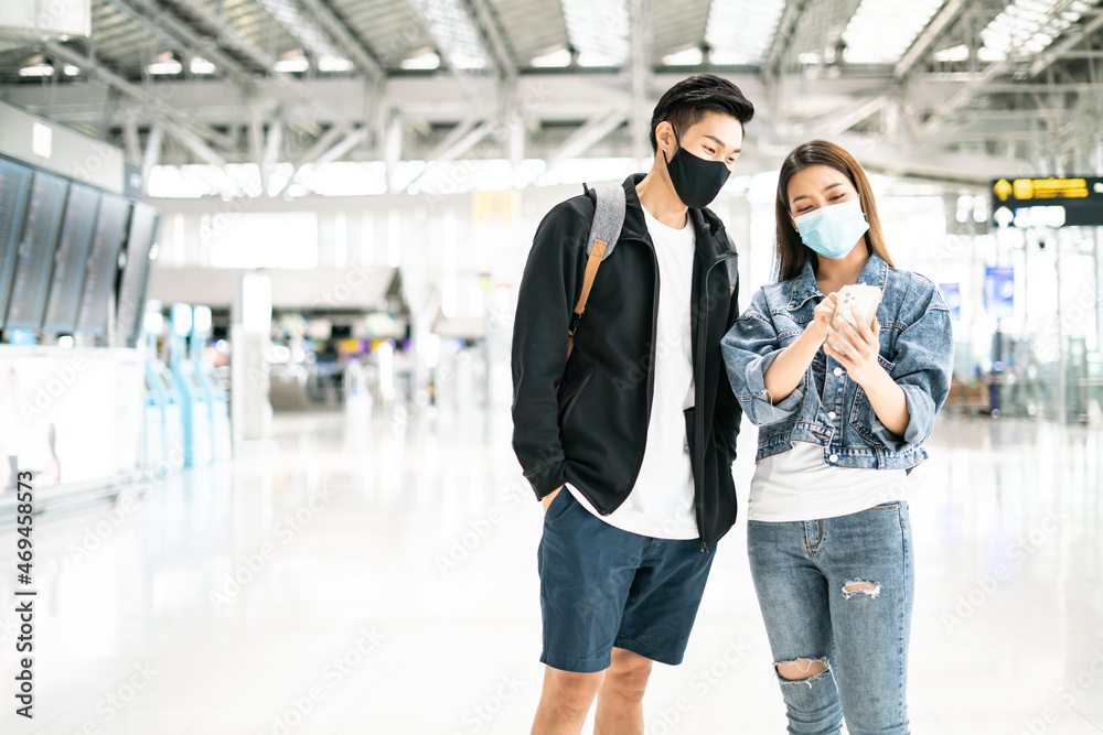 New normal,bubble travel and social distancing concept.Traveler man and woman wearing face mask and waiting to board at terminal airport for protection coronavirus(covid-19) during virus pandemic