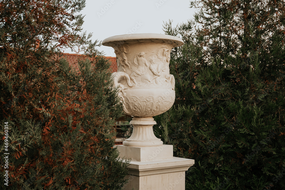 large white stone flowerpot against the backdrop of the greenery of the park large white stone flowerpot against the backdrop of the greenery of the park