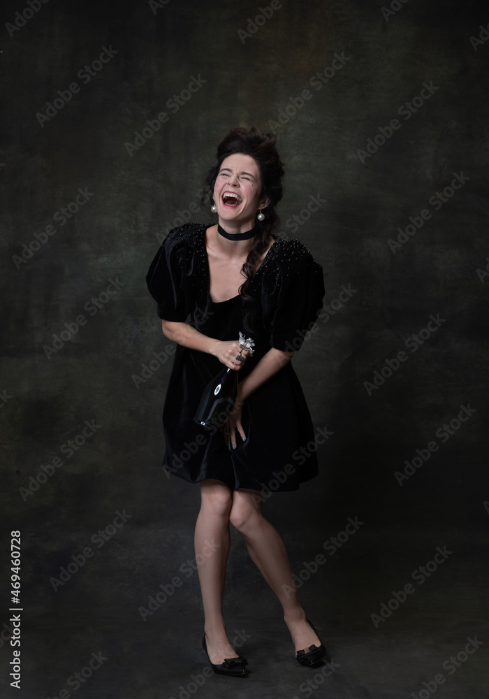 Full-length portrait of young beautiful happy woman in black holiday attire drinking wine and laughing isolated on dark vintage background. Full-length portrait of young beautiful happy woman in black holiday attire drinking wine and laughing isolated on dark vintage background.