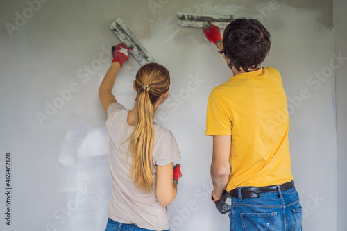 A man and a woman are plastering the walls of the house. DIY home renovation