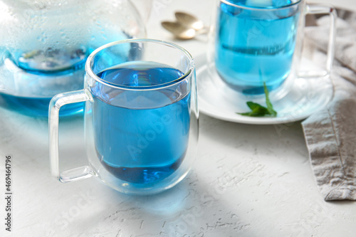 Glass cup of blue tea on light background, closeup photo