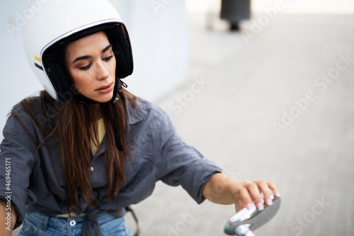 Beautiful woman getting ready for a ride on scooter. Beautiful happy lady having fun outdoors