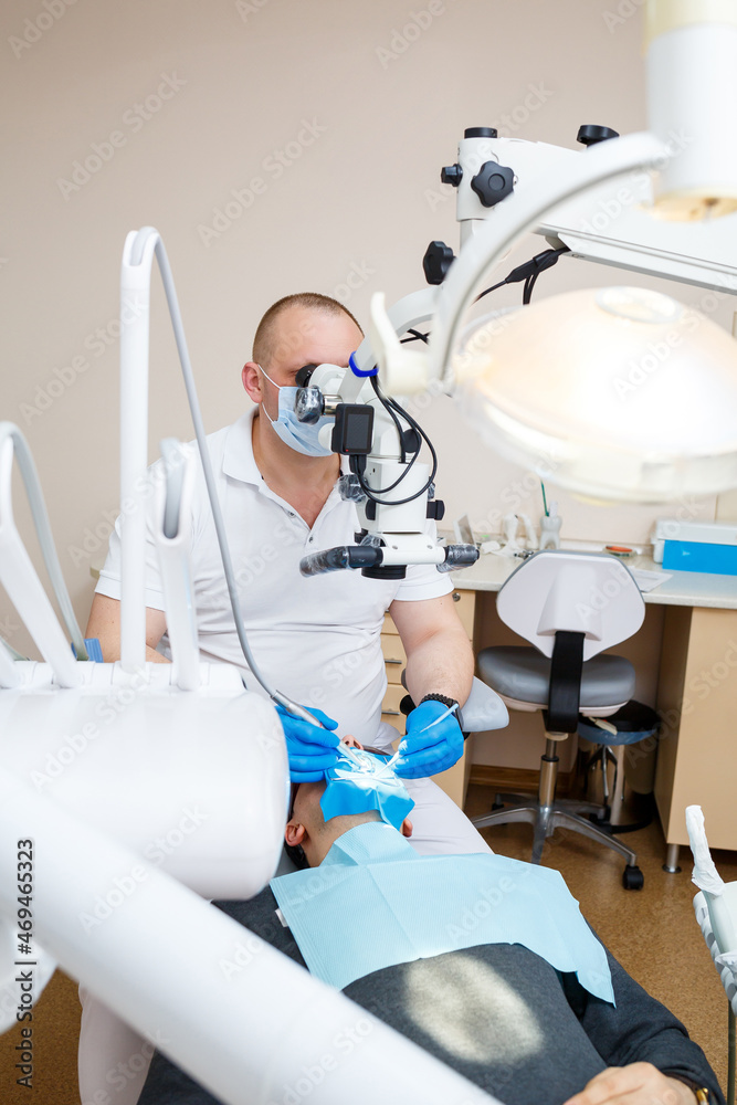 Fototapeta premium The dentist treats his patient's teeth with a microscope. The dentist treats the patient's mouth. Dental care