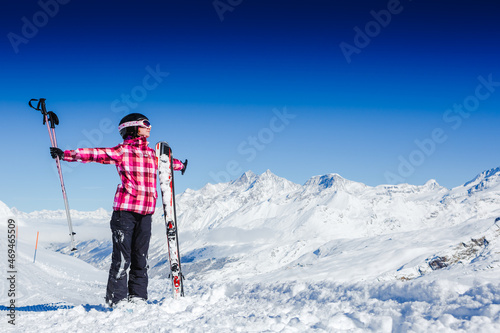 Young happy girl in snowy mountains with skis enjoying winter time