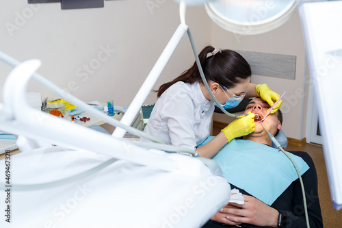 The dentist in the office treats the teeth of the patient who is in the dental chair. dentistry. The dentist puts a dental filling on his patient. Oral care